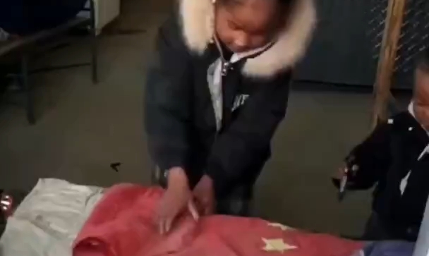 窗户内的暖心一幕，小姑娘认真叠好旧国旗