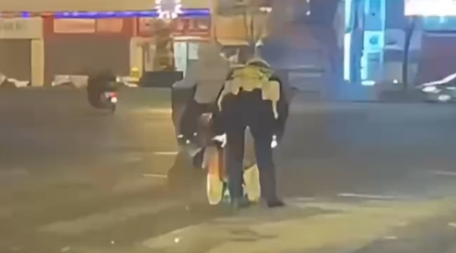 警察叔叔俯身清扫路面散落的渣土