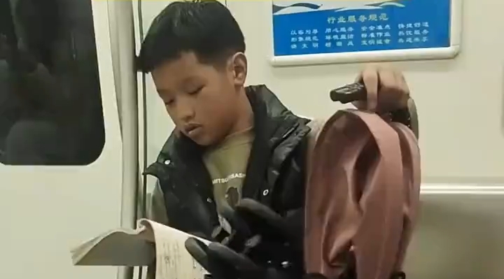 藏族小男孩守着一旁的婴儿车认真读书