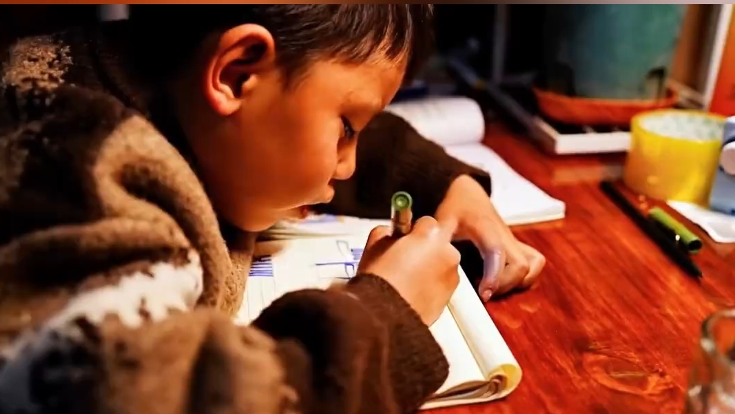 父亲拍下孩子认真读写藏文的瞬间