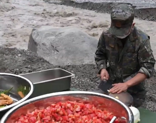 湍急水流旁,他们为救援人员架起锅灶